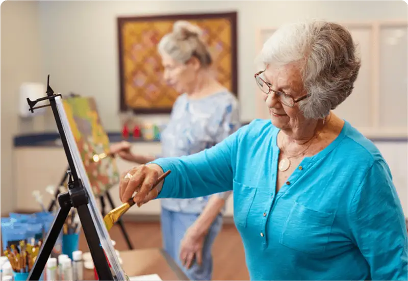 Senior painting on canvases in an art studio