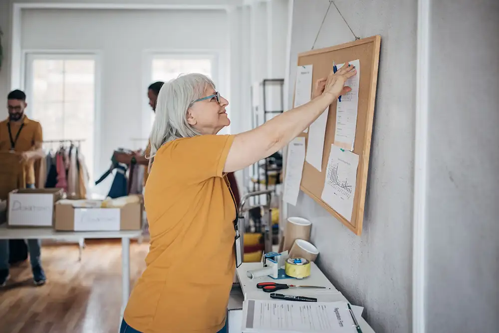 Volunteer posting activities on a cork board