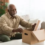 Senior Man Packing Stuff Putting His Belongings In Cardboard Box