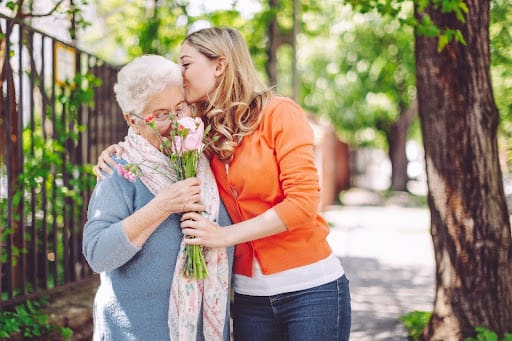 granddaughter kissing grandmother outside on the forehead outside