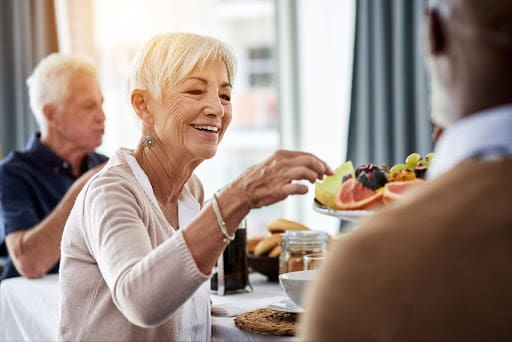 A senior woman reaches for another piece of fruit from an exquisite fruit plate