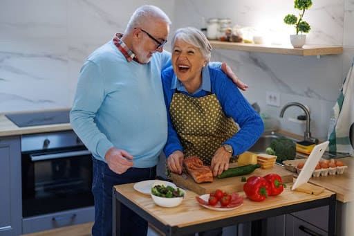 Two seniors enjoy preparing a heart healthy meal for seniors together