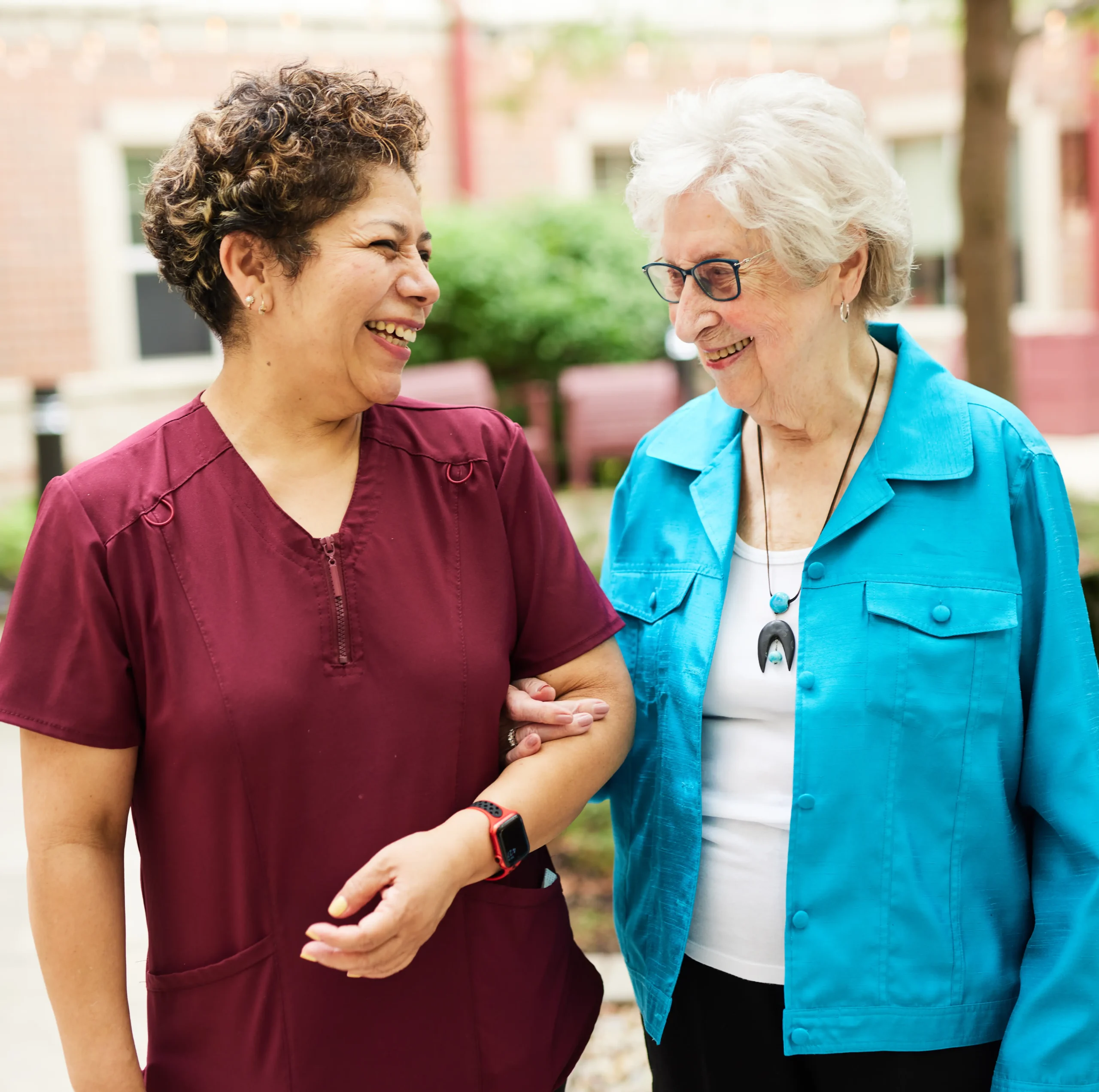 Caretaker and Elderly woman laughing while walking